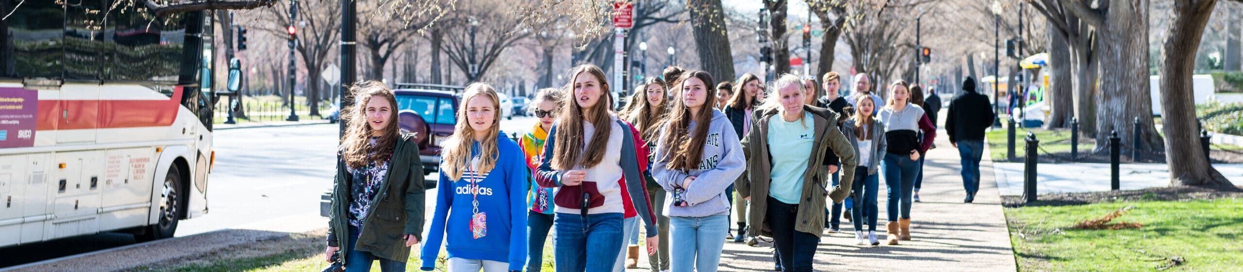 Group of high school children, girls walking on sidewalk of Constitution Avenue in District of Columbia on sightseeing day field trip in spring